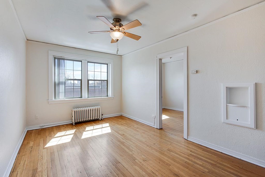 A room with a ceiling fan and a window with a radiator beneath it.