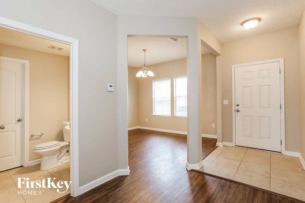 an empty living room with a white door and a bathroom