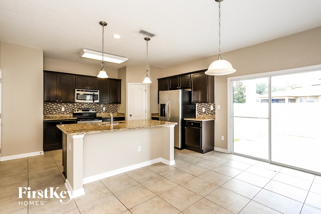 a kitchen with a large island and a stainless steel refrigerator
