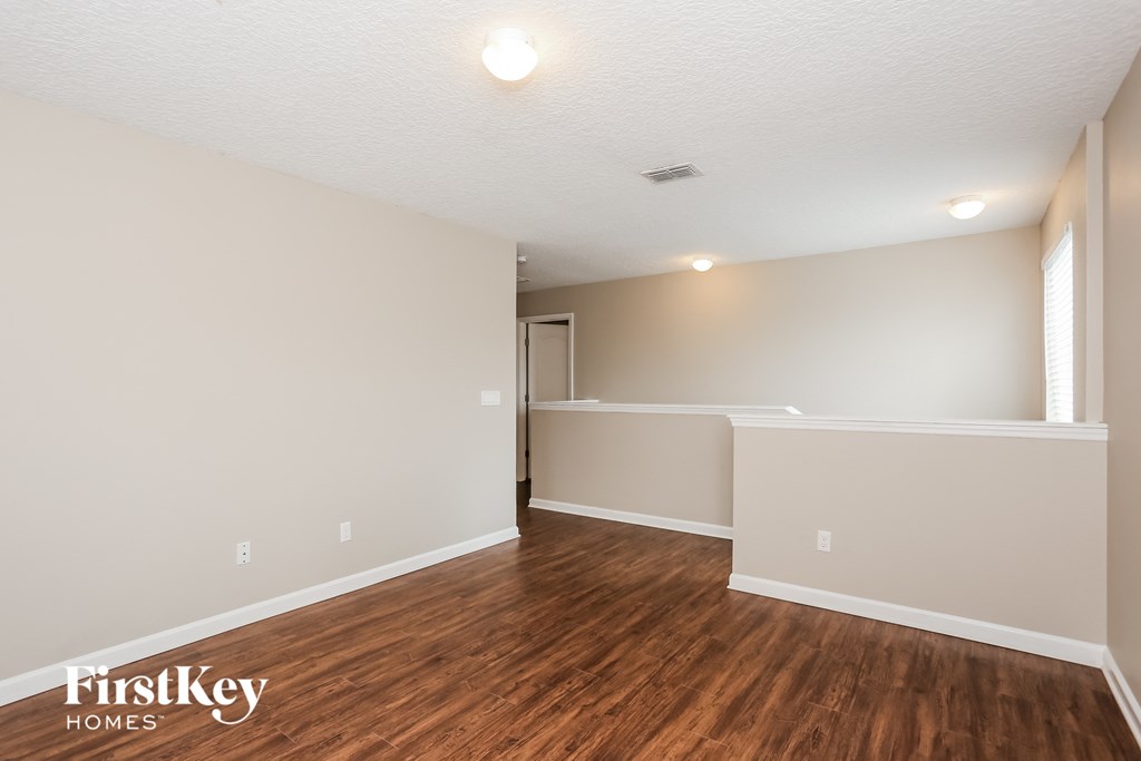 the living room and dining room with hardwood floors and white walls