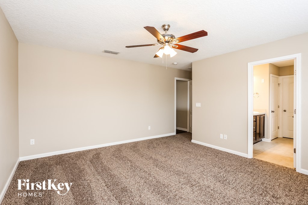 a spacious living room with carpet and a ceiling fan
