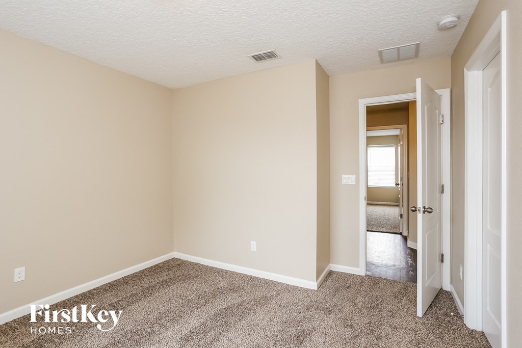 a bedroom with carpet and a door to a hallway