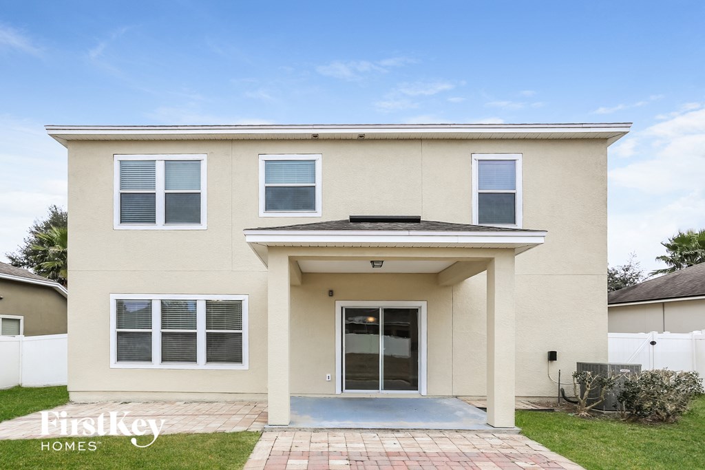 the front of a tan house with a driveway and grass
