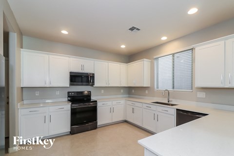 A kitchen with white cabinets and appliances, and a FirstKey Homes logo.