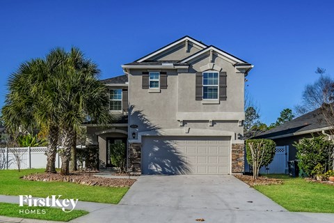 a house with a garage door and palm trees