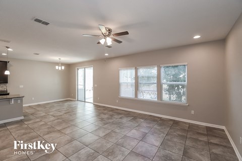 an empty living room with a ceiling fan and a window