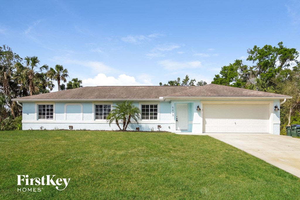 A white house with a brown roof and a garage door.