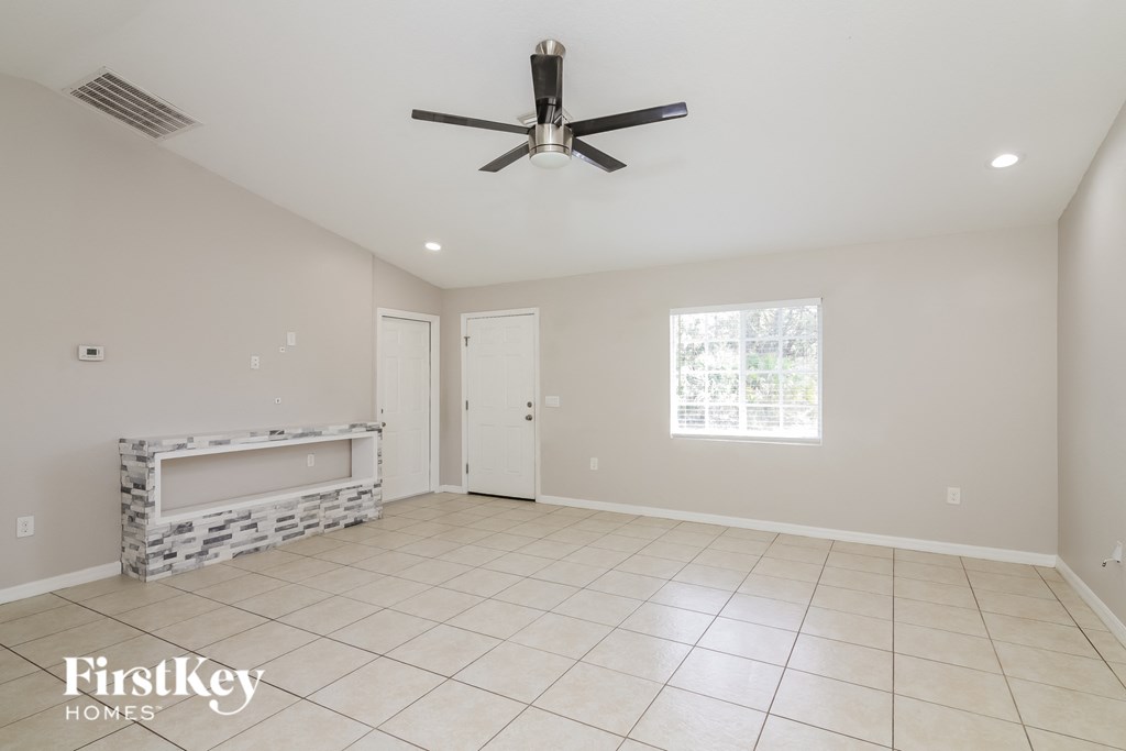 A spacious room with a ceiling fan and a large window.
