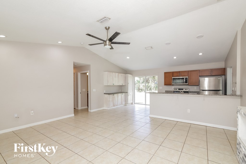 A spacious kitchen and living room with a ceiling fan.