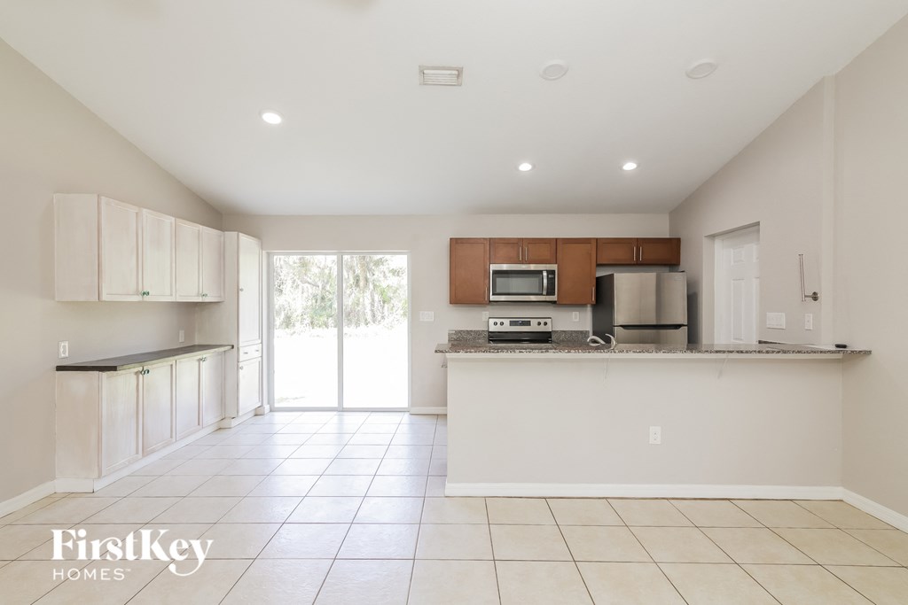 A kitchen with white cabinets and a tiled floor.