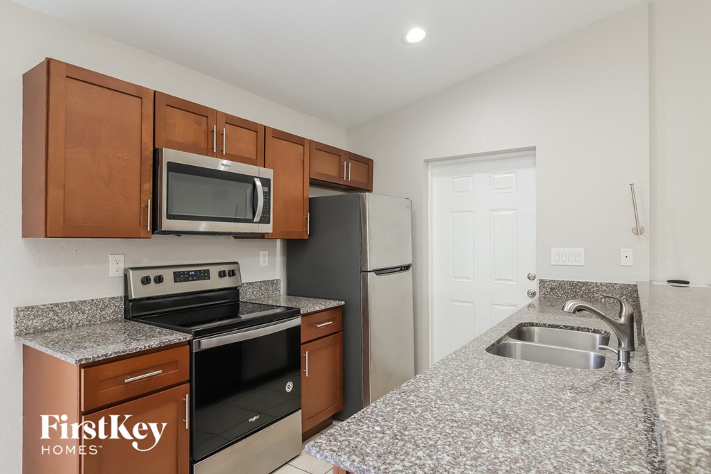 A kitchen with a stove, microwave, and refrigerator.