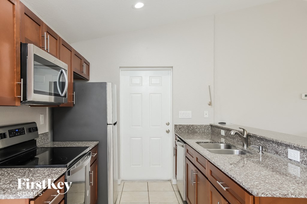 A kitchen with brown cabinets and a black stove top oven.