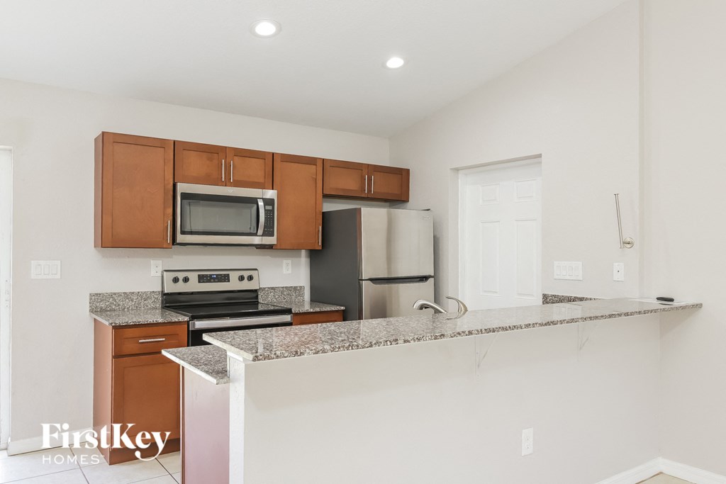 A kitchen with a stove top oven, microwave, and refrigerator.