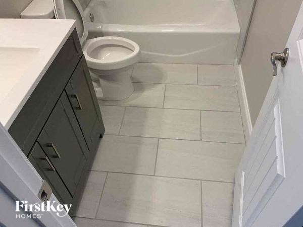 A white toilet in a bathroom with a white tiled floor.