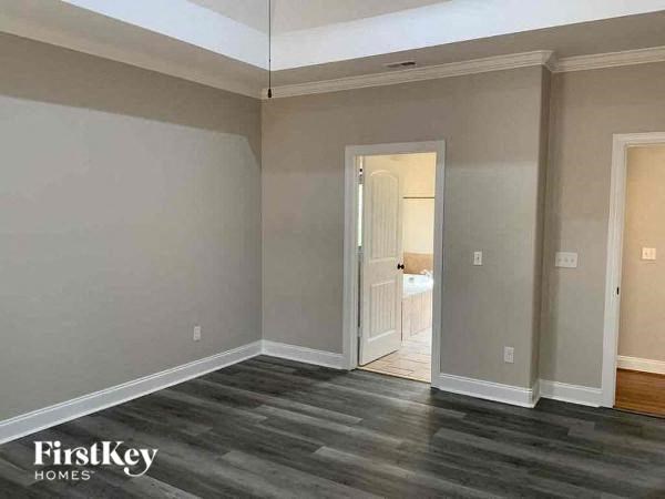 A room with wooden flooring and a doorway leading to another room.