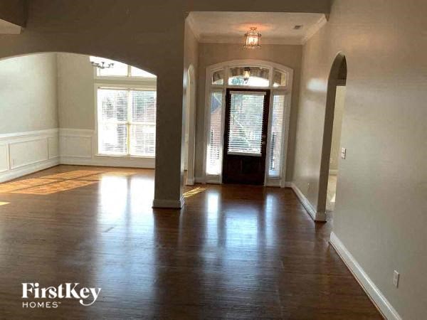 A spacious room with wooden floors and arched doorways.