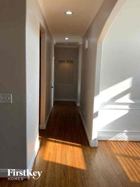 A long hallway with wood floors and white walls.