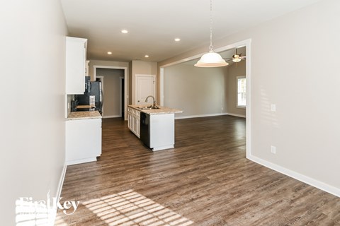 A kitchen with white cabinets and a wooden floor.