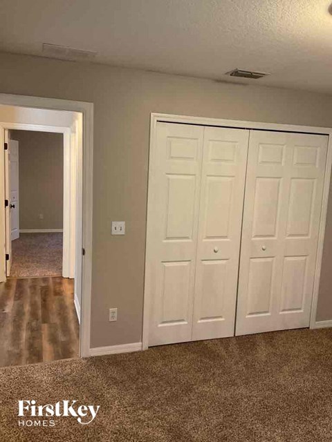 an empty bedroom with two closets and a hallway with a door to a bathroom