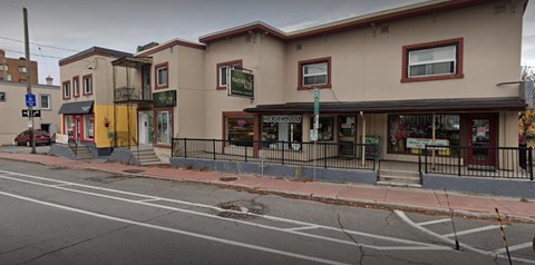 A street view of a building with a green sign that says "The Pink House".
