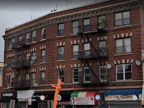 A building with a red brick facade and a balcony with a black railing.