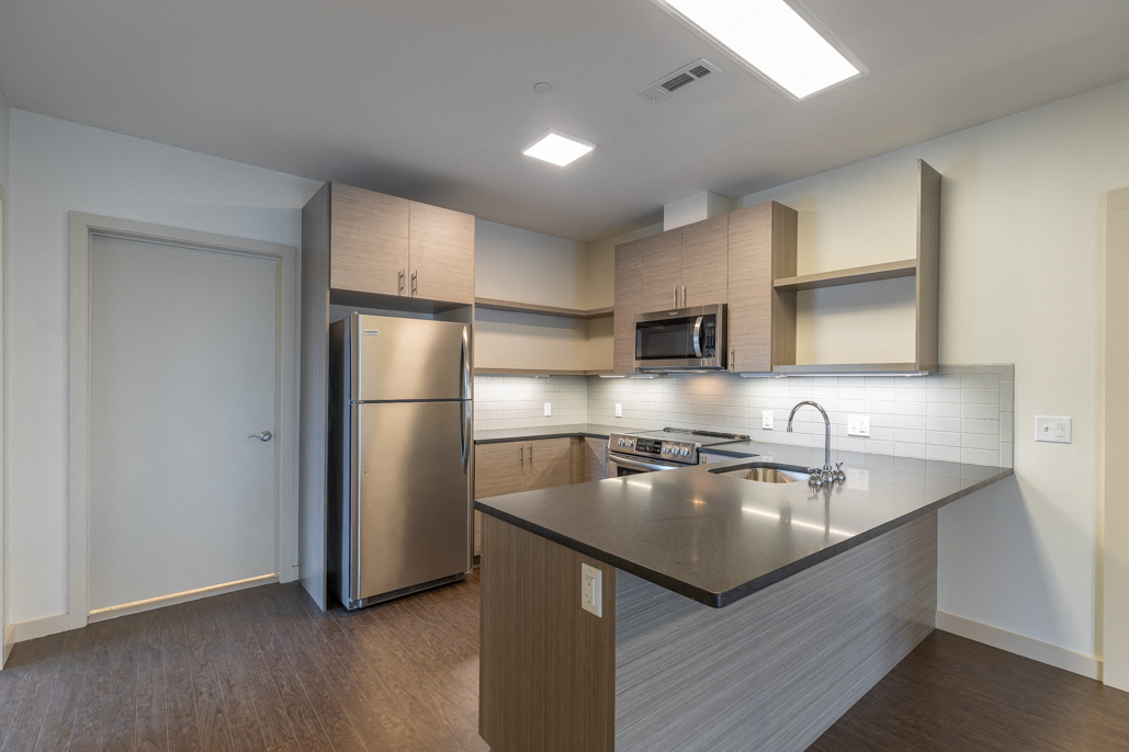 a kitchen with a large island and a stainless steel refrigerator