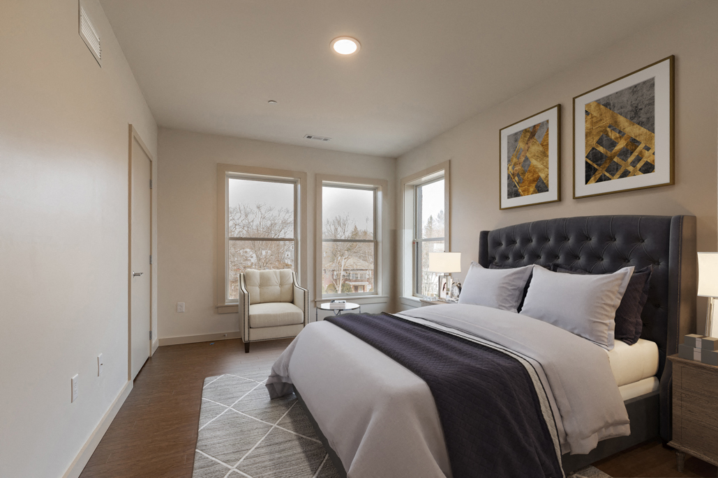 a bedroom with a bed and a chair and windows