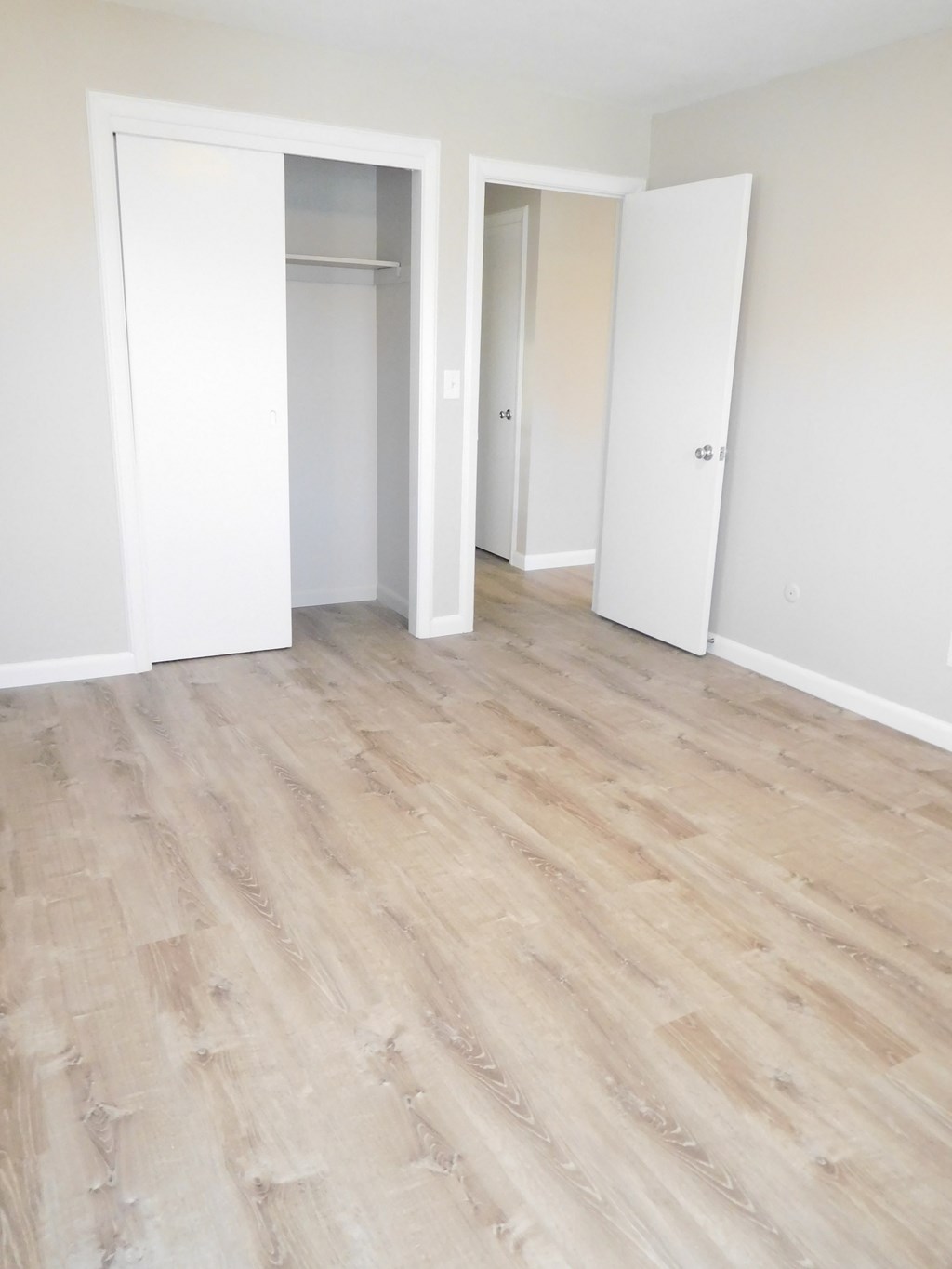 an empty room with white walls and a wood floor