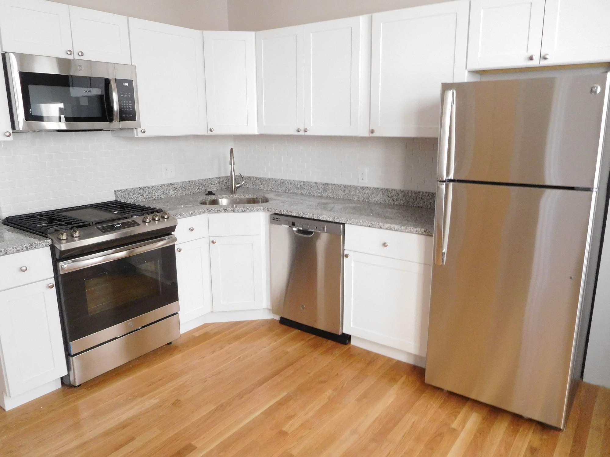 Renovated Kitchen with White Cabinets, Granite Counters, Stainless Appliances and Hardwood Floors