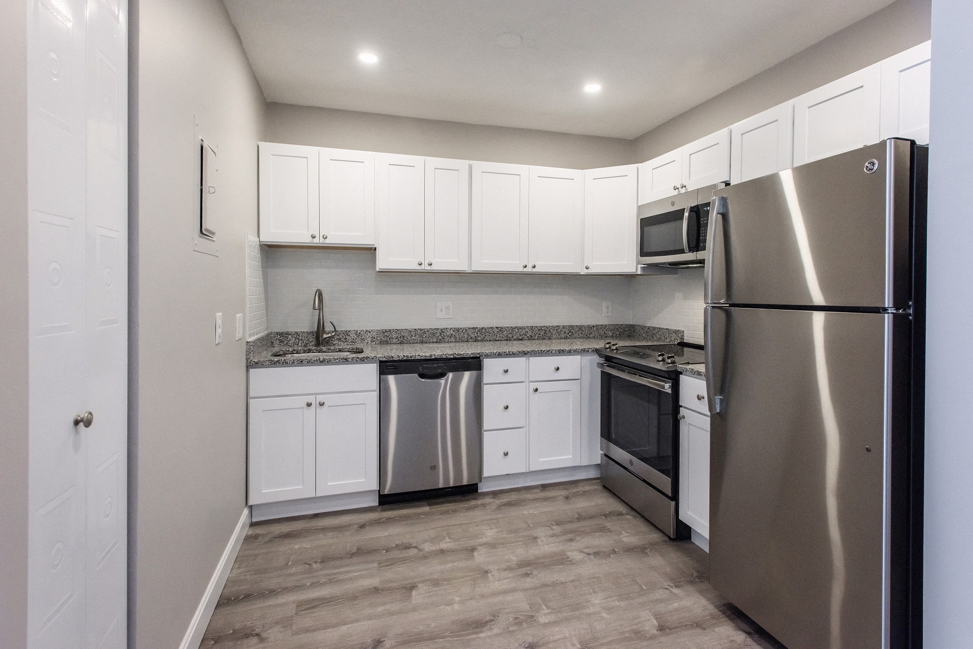 an empty kitchen with stainless steel appliances and white cabinets