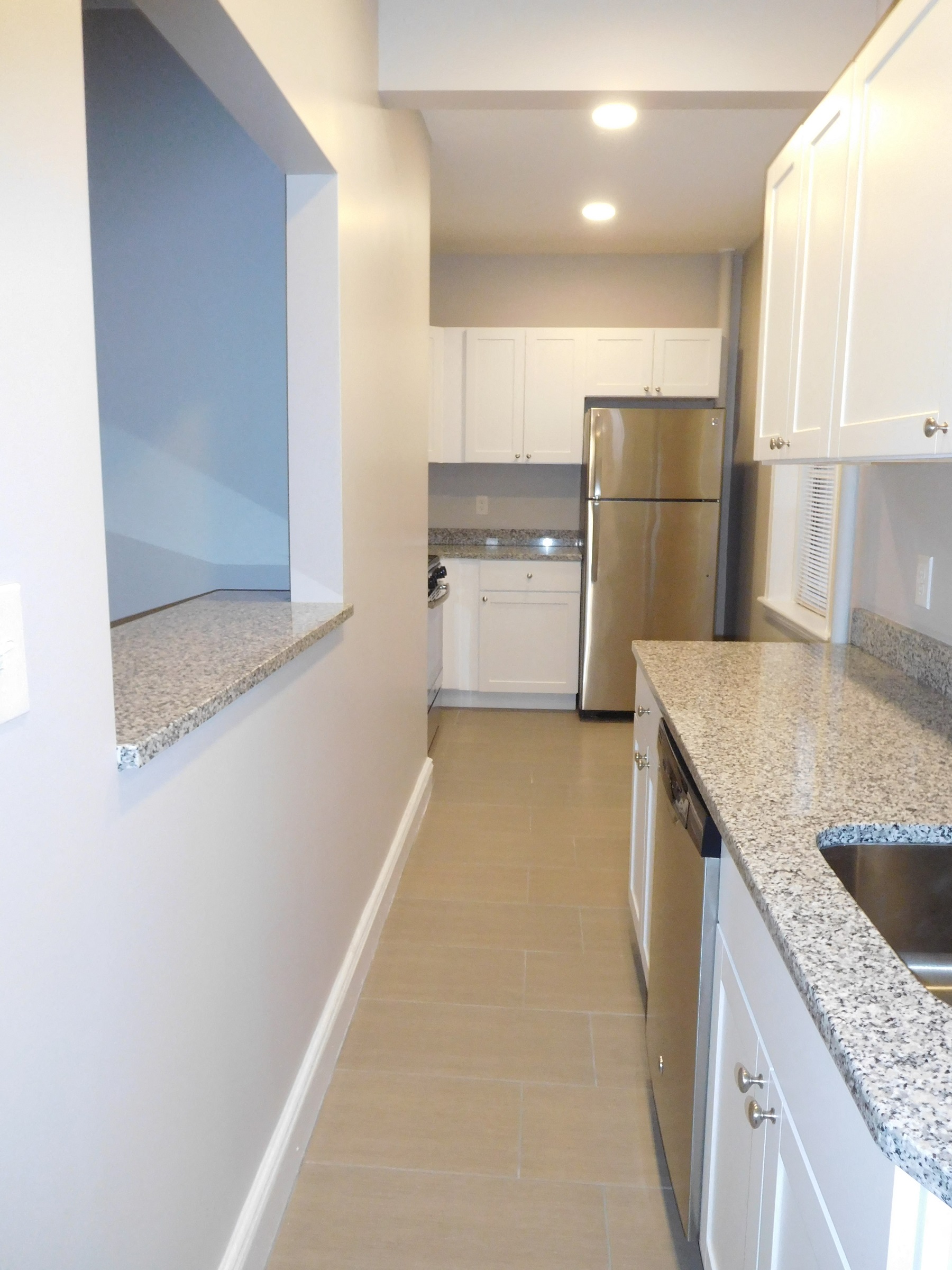 a kitchen with white cabinets and granite counter tops and a stainless steel refrigerator