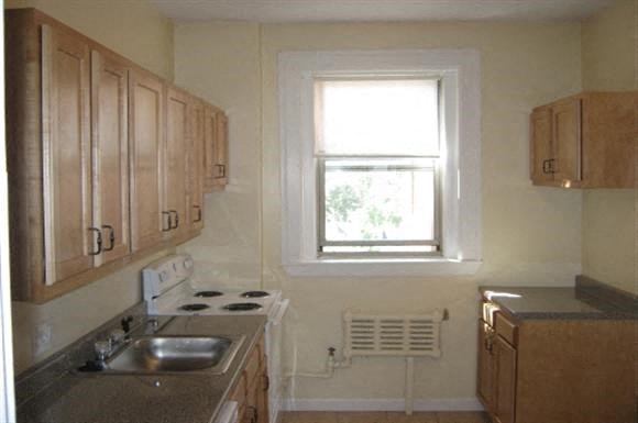 a kitchen with a stove and a sink and a window