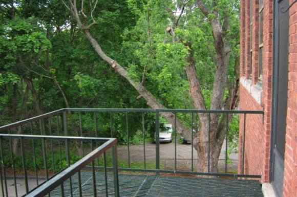 a balcony with a tree and a car in a driveway