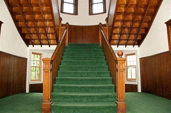 a staircase in a large room with green carpet