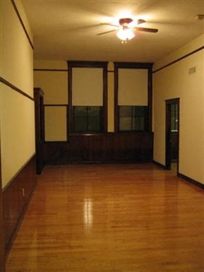 an empty room with a wood floor and a ceiling fan