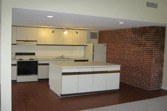 an empty kitchen with a brick wall