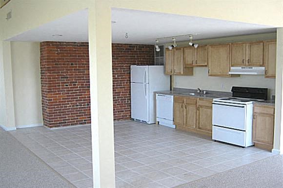 an empty kitchen with white appliances and wooden cabinets
