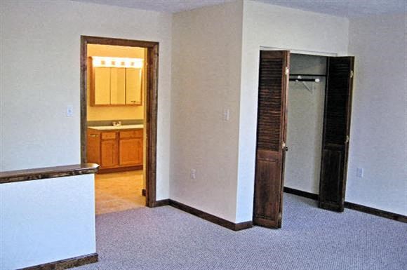 an empty living room with a door to a bathroom