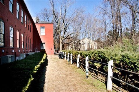 an old red brick building with a dirt path and a fence
