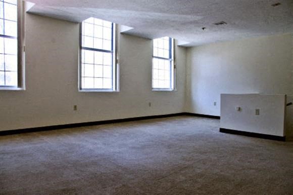 an empty room with three windows and a radiator