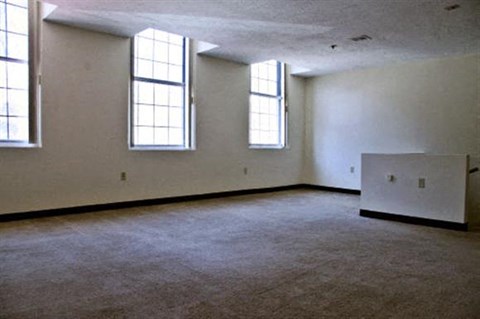 an empty room with three windows and a radiator