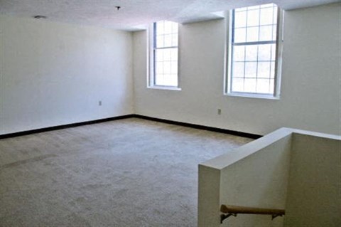 an empty room with white walls and two windows
