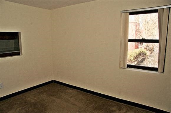 an empty room with a window and a brown floor