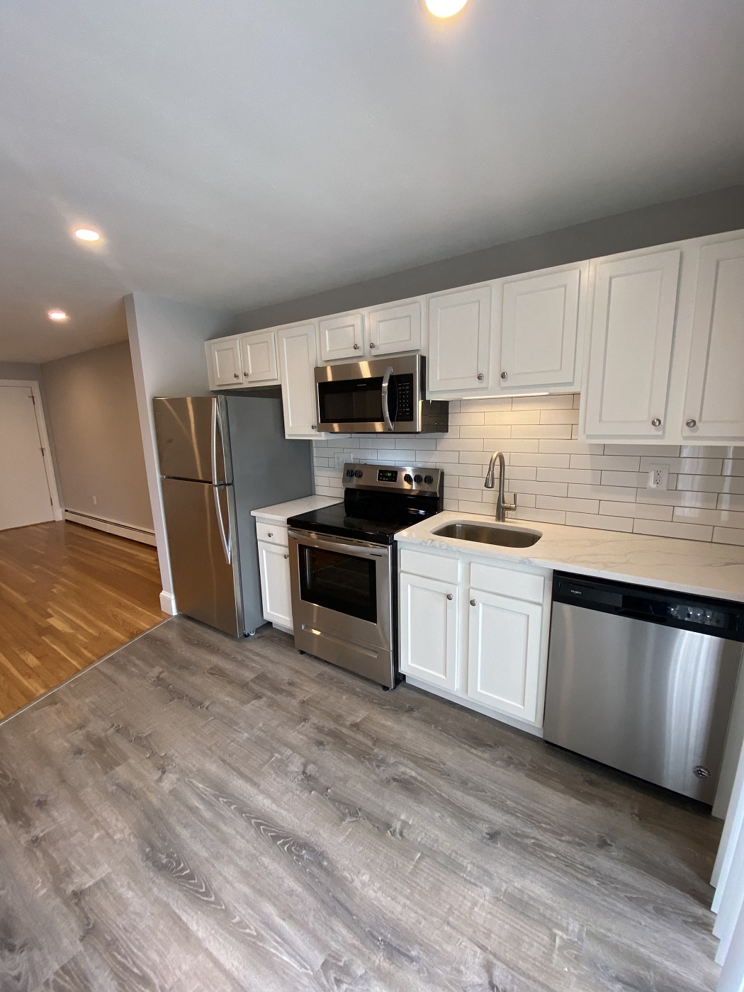 Renovated kitchen with white cabinets, quartz counters and stainless appliances