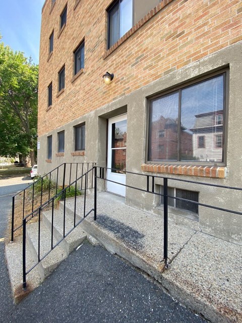 the front entrance of a brick building with black railings