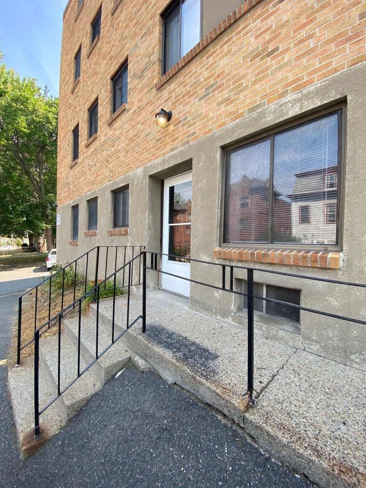 the front entrance of a brick building with black railings