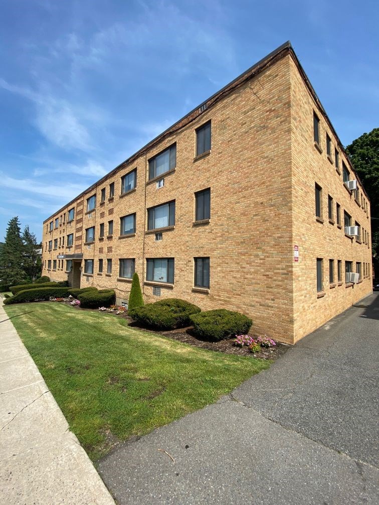 a brick building with grass and bushes in front of it