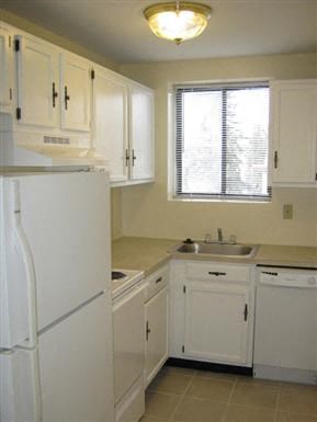 a kitchen with white cabinets and a sink and a refrigerator