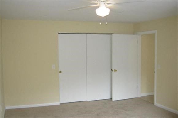 an empty living room with a ceiling fan and a closet