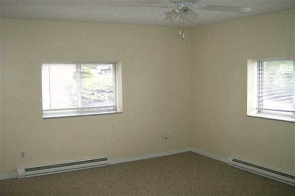 an empty room with two windows and a ceiling fan